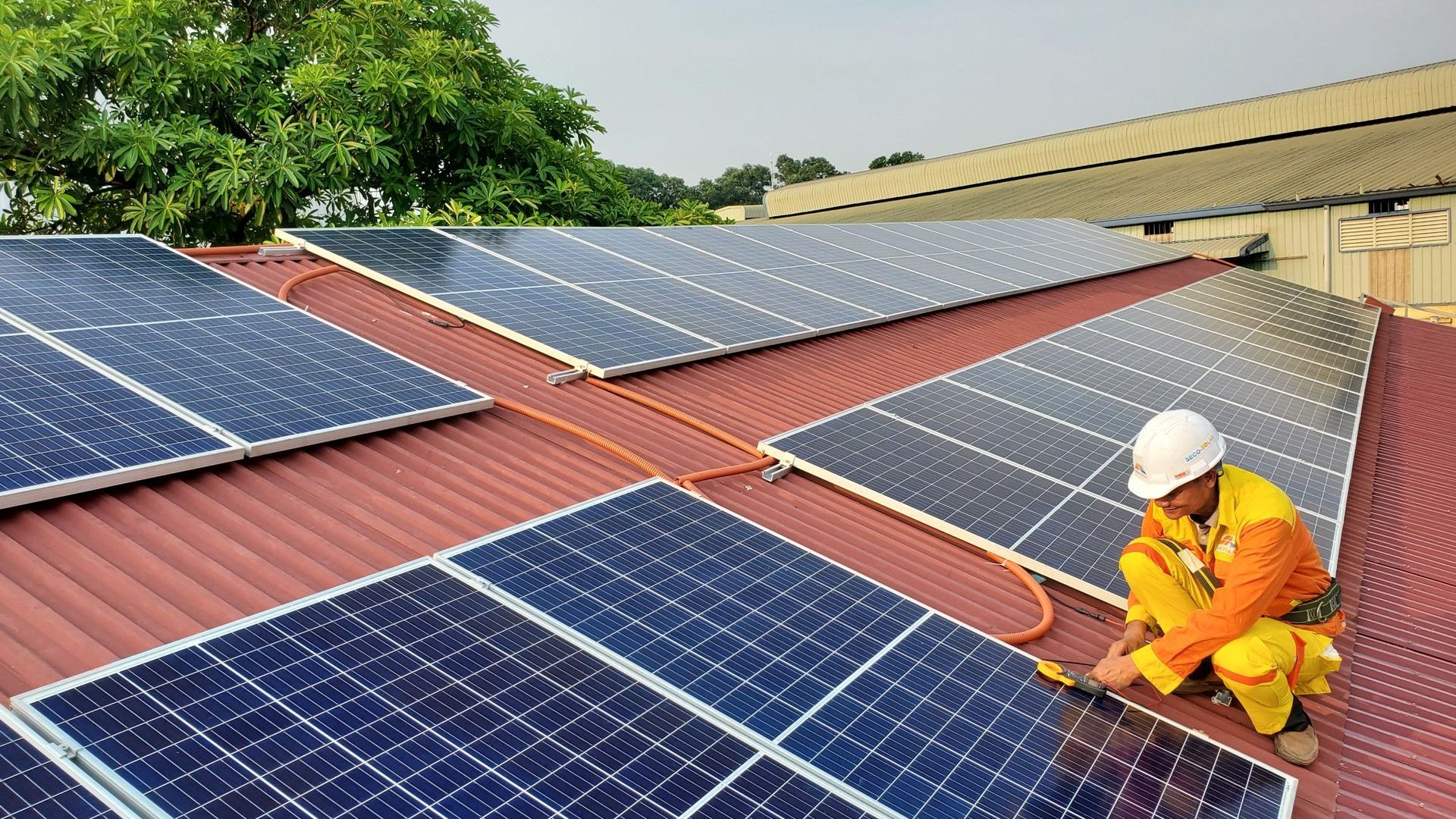 Techniker montiert Photovoltaikmodule auf einem Ziegeldach