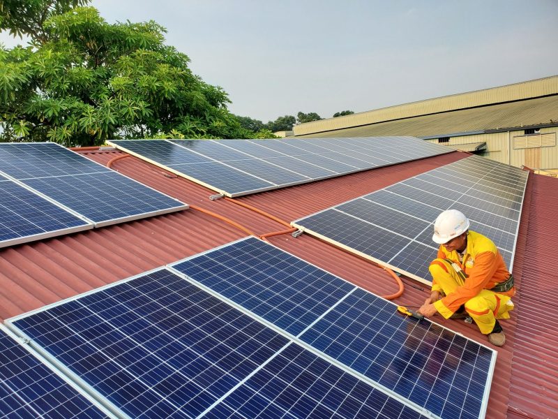 Techniker montiert Photovoltaikmodule auf einem Ziegeldach