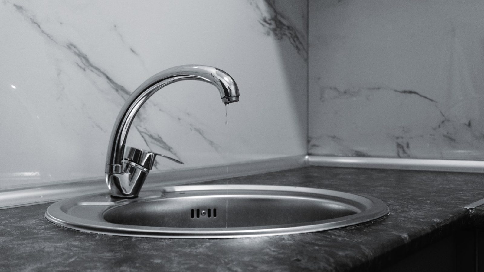 Tropfender Wasserhahn an Marmor-Waschbecken, klares Wasser