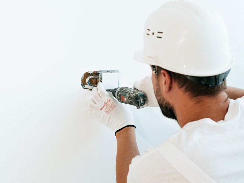 Elektriker montiert Steckdose an einer weißen Wand